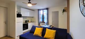 a living room with a blue couch and yellow pillows at Colonial - Élégant deux-pièces à 20min de Rouen in Caudebec-lès-Elbeuf
