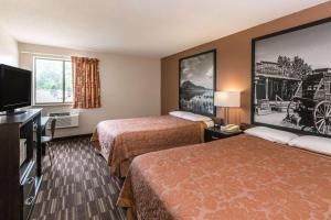 a hotel room with two beds and a flat screen tv at Super 8 by Wyndham Madison in Madison