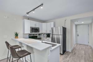 Una cocina con gabinetes blancos y un refrigerador de acero inoxidable. en Mulberry, a Wyndham Hotel, en Vicksburg