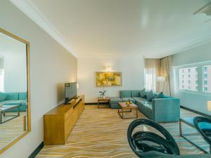 a living room with a couch and a tv at Copthorne Downtown by Millennium in Abu Dhabi