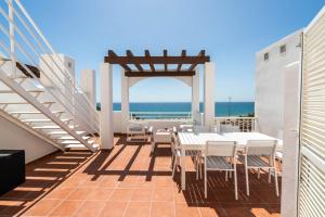 a balcony with white tables and chairs and the ocean at AlmeriaSuite Mojacar Breeze Apartments in Mojácar