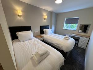 two beds in a hotel room with towels on them at The Wyken Inn in Coventry