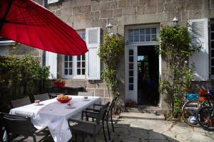 a table with a red umbrella in front of a building at Splendide maison de maître à 50m du port et 100m de la plage in Barfleur