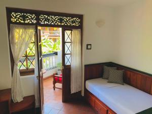 1 dormitorio con cama, ventana y ventana en Blue Swan Inn, en Unawatuna