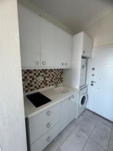 een keuken met witte kasten en een wasmachine bij Turap Homes in Antalya