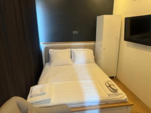 een kleine slaapkamer met een bed met witte lakens en een televisie bij Turap Homes in Antalya +1 foto