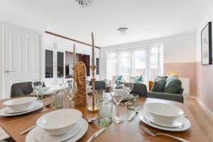 a dining room with a table with plates and glasses at Stylish & Chic 3 bed House in Cambourne