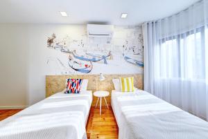 two white beds in a room with a wall at Hotel do Mercado in Aveiro