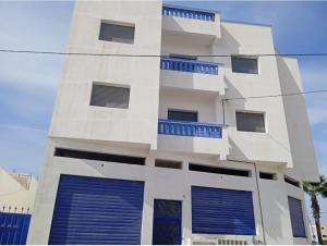 a white building with blue windows and blue doors at Appartement familial 2 in Oualidia