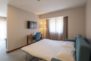 um quarto de hotel com uma cama, uma mesa e uma secretária em Hotel Navarras em Amarante