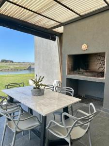 a table and chairs on a patio with a fireplace at Casa familiar a la laguna en San Sebastian, Escobar, 3 dormitorios, jardín, pileta, parrilla y canoas in Zelaya