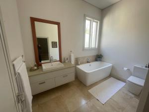 a bathroom with a tub and a sink and a mirror at Jakaranda Cottage in Somerset West