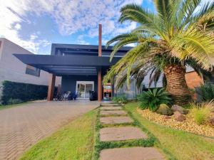 a palm tree in front of a house at Casa de Verão no Malibu à Beira do Lago in Xangri-lá