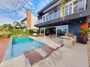 a house with a swimming pool and a patio at Casa de Verão no Malibu à Beira do Lago in Xangri-lá