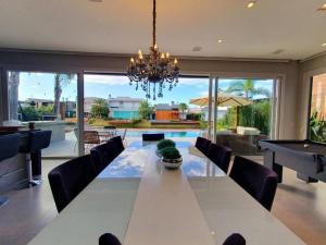 a dining room with a long table and a pool table at Casa de Verão no Malibu à Beira do Lago in Xangri-lá