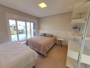 a bedroom with two beds and a window at Casa de Verão no Malibu à Beira do Lago in Xangri-lá +24 photos