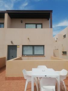 une table blanche et deux chaises blanches devant un bâtiment dans l'établissement Casa en Cotillo Lagos with Wifi & Netflix, à El Cotillo
