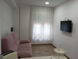 a living room with a couch and a tv on a wall at Hospedaje Magallanes in Santander