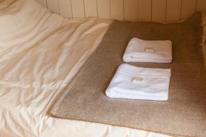 a bed with two white towels on it at Daisy Shepherds Hut in Kent
