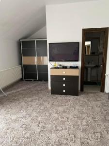 a living room with a tv and a dresser at Pensiunea Floris in Vaţa de Jos