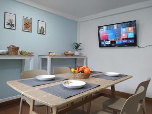 a dining room table with a television on a wall at Living Room Udonthani in Udon Thani