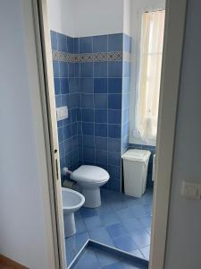a blue tiled bathroom with a toilet and a sink at Rue HENRY BENNET in Menton
