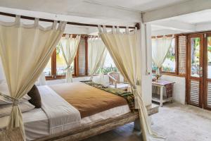 a bedroom with a canopy bed with curtains at Cemara Beachfront Suite in Mondu +43 photos