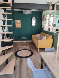 a living room with a yellow couch and a green wall at La grange aux animaux in Tollevast