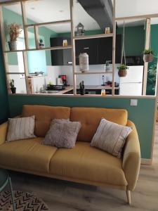 a brown couch in a living room with a kitchen at La grange aux animaux in Tollevast