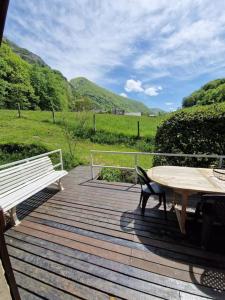 une terrasse en bois avec une table et un banc dans l'établissement Chalet à la Montagne, à Sainte-Marie-de-Campan