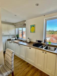 a kitchen with white cabinets and a sink and a window at Family Home in Seaside Town in Hastings
