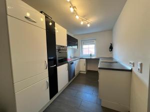 a kitchen with white cabinets and a black refrigerator at Ferienwohnungen Hopfenhaus in Spalt +6 photos