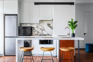 a kitchen with a white counter and two stools at Boulevard 115 in Tashkent