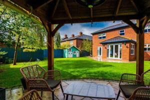 a patio with chairs and a table in a yard at Spacious Comfort for Contractors & Long-Term Guests in Saighton