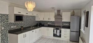 a kitchen with white cabinets and a stainless steel refrigerator at 4-Bed Charming Pet-Friendly House w Garden in Peterborough +5 photos