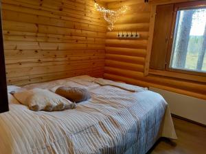 a bedroom with wooden walls and a bed with pillows at Ylläs Valokki in Ylläsjärvi