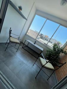 2 sillas y una mesa en una habitación con ventanas grandes en Cómo en casa, en Resistencia