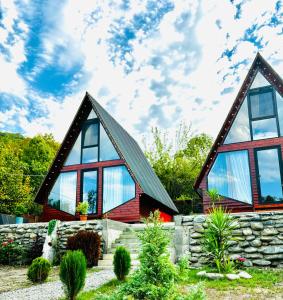 a house with large windows and a stone wall at Off in racha in Dzirageuli