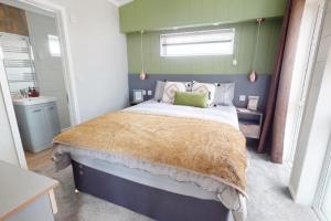a bedroom with a large bed with green walls at Pebble Beach Resort The Goodwood Lodge in Kinmel Bay