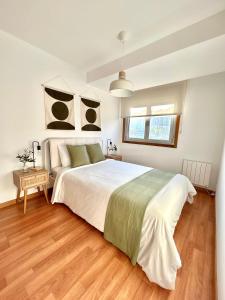 une chambre avec un grand lit blanc et un parquet dans l'établissement Apartamento Enseñanza - Barco a Vigo Gratis - Kid Friendly, à Cangas