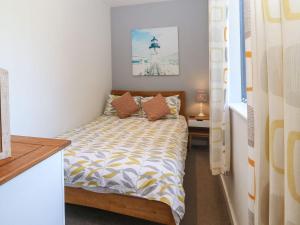 a small bedroom with a bed with orange pillows at Victoria House in Rhosneigr