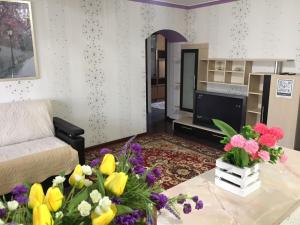 a living room with a couch and flowers on a table at Трешка микрорайон Саулет 11 in Qyzylorda