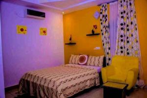 Un dormitorio con una cama y una silla dentro. en MDI Résidence officiel, en Abiyán