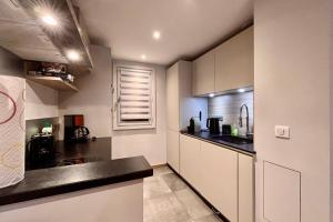 a kitchen with white cabinets and black counter tops at Lachat 15 in Mussillon +20 photos