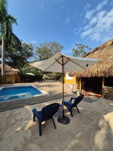 Ecoluxury Villa Yakarta Playa artificial minicine في ميلغار: كرسيين ومظلة بجانب مسبح