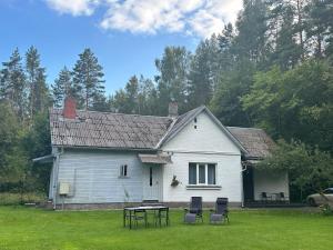 ein weißes Haus mit Stühlen und einem Tisch im Hof in der Unterkunft Strawberry Forest in Jūrmala