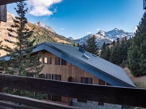a house with a metal roof with mountains in the background at Condo Méribel Mottaret - Ski aux pieds, 3 chambres, 8 pers, WIFI - FR-1-355-202 in Les Allues
