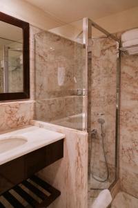 a bathroom with a shower and a sink and a mirror at Princess Resort, Santikos Collection in Agia Paraskevi