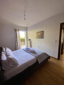 a bedroom with a bed with white sheets and a window at PATIMA Chalandri House in Athens