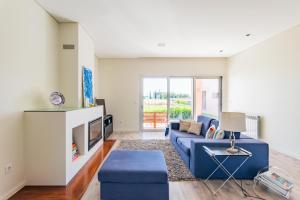 a living room with a blue couch and a tv at Villa Joana - Moradia premium em Aveiro in Esgueira